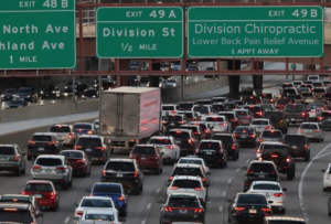 Chicago traffic jam with a highway exit labeled “Division Chiropractic - Lower Back Pain Relief Avenue" and it's "1 appointment away."